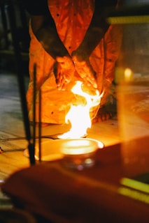 man in brown leather jacket holding a stick with fire