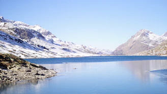 A serene aerial image of a mountain lake reflecting the surrounding snow-capped peaks.