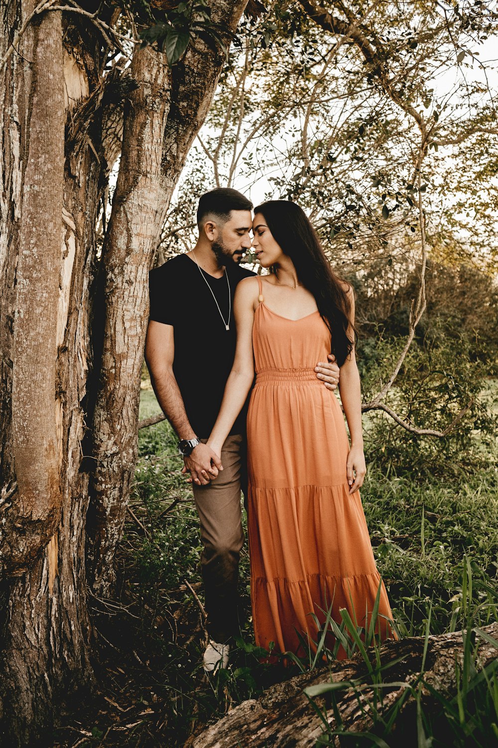 man and woman standing beside tree during daytime