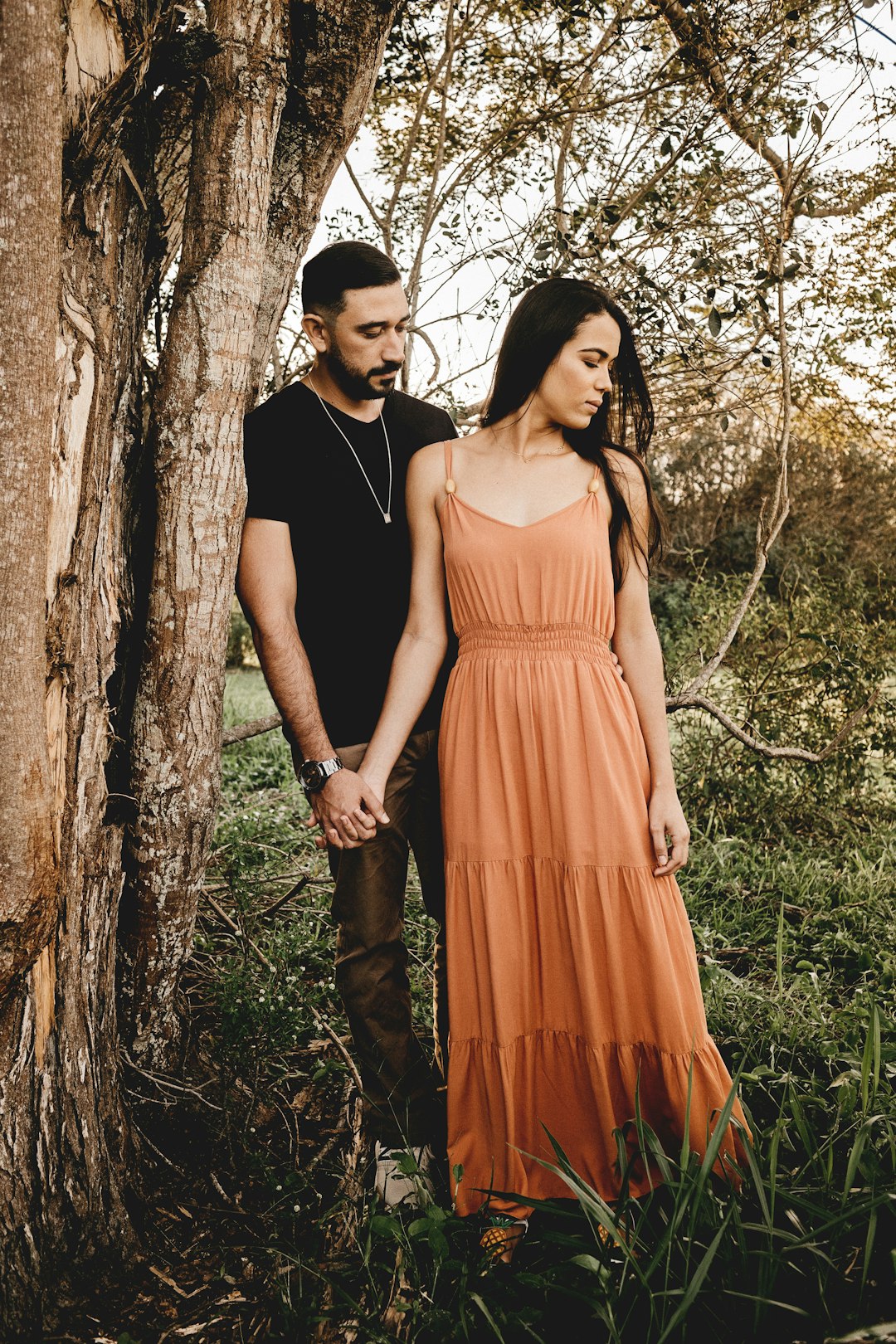 woman in orange dress standing beside man in black suit