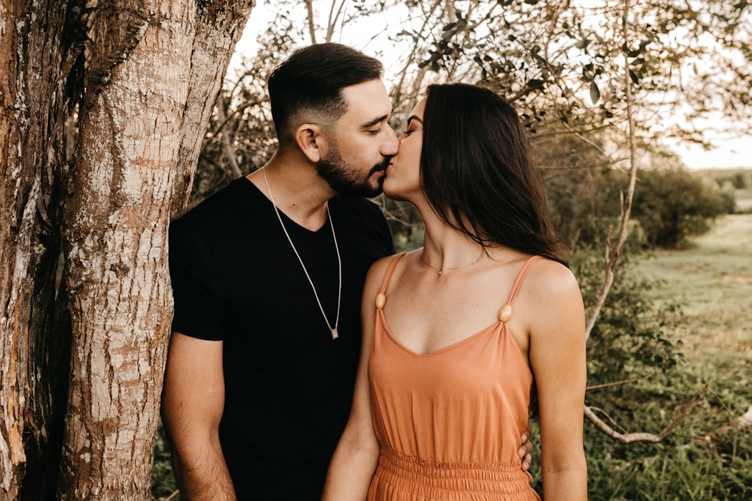 man and woman kissing under tree during daytime