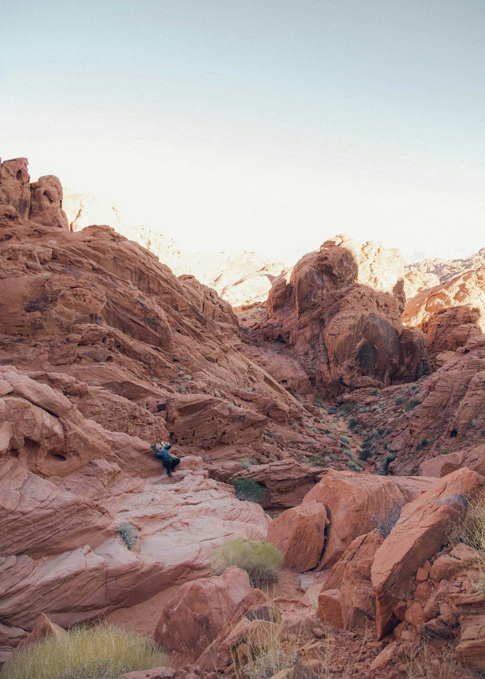 person in blue jacket sitting on brown rock formation during daytime