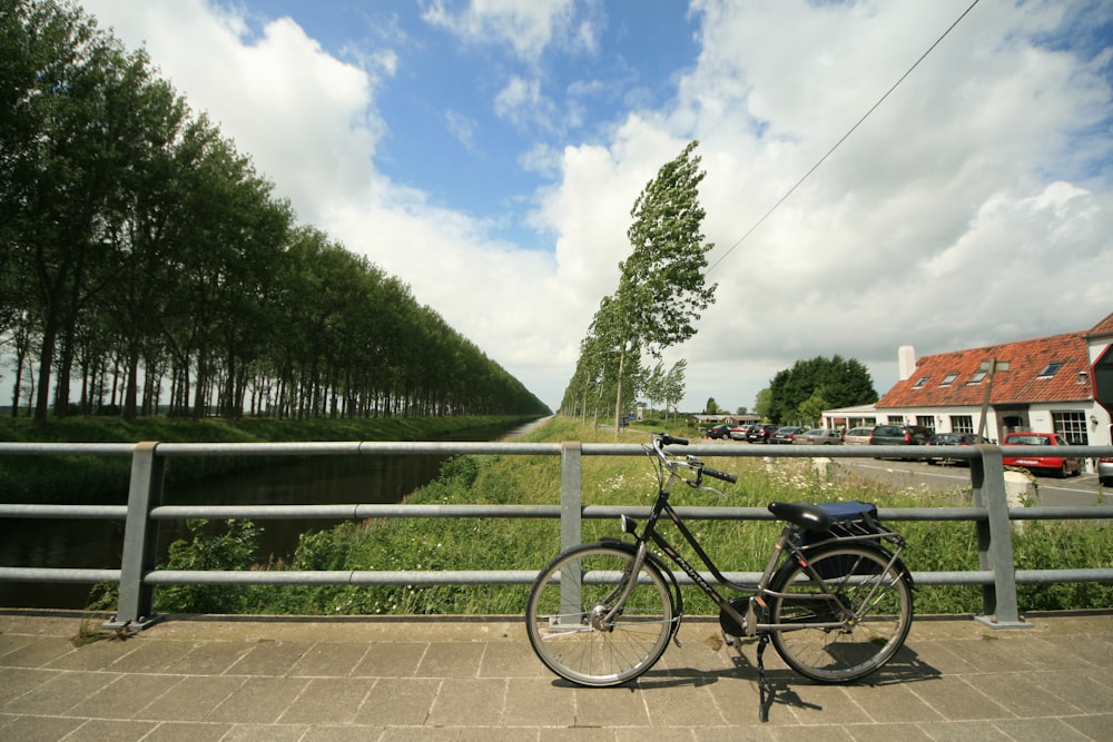 black bicycle parked beside green metal fence