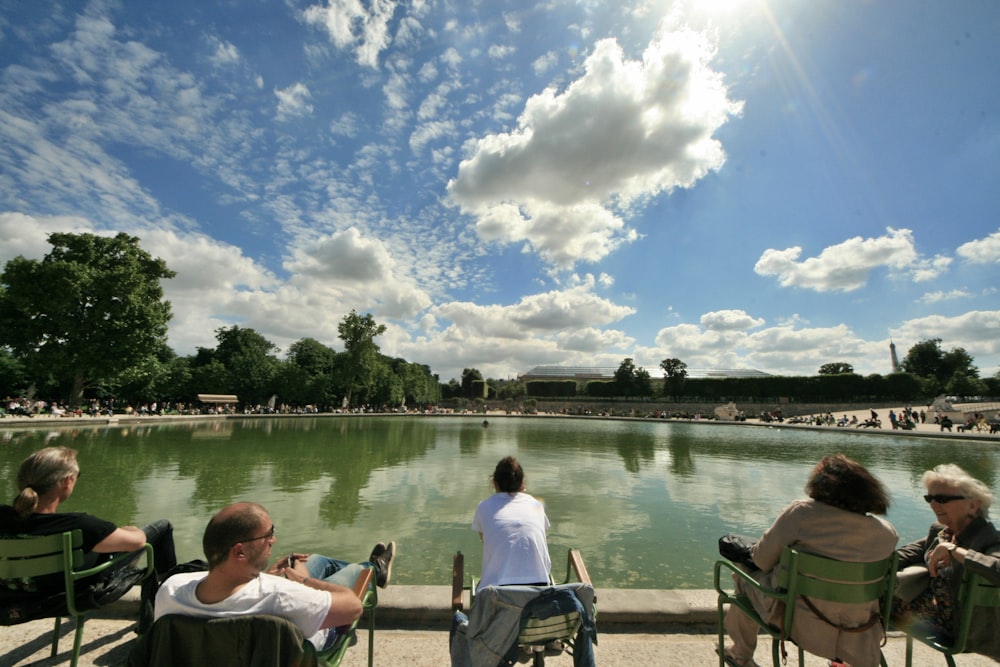 man and woman sitting on brown wooden bench near body of water during daytime