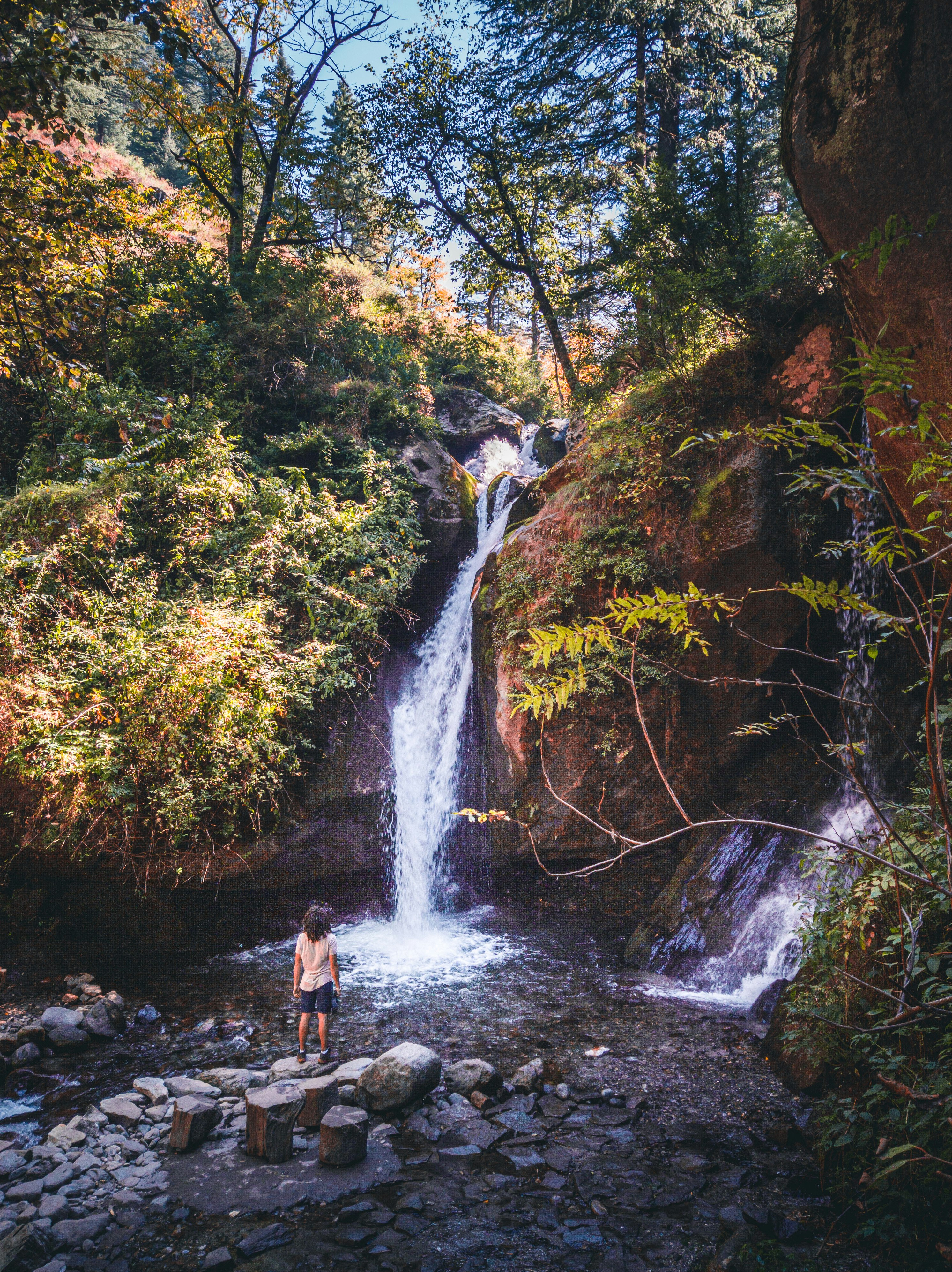 person standing on rock near waterfalls during daytime