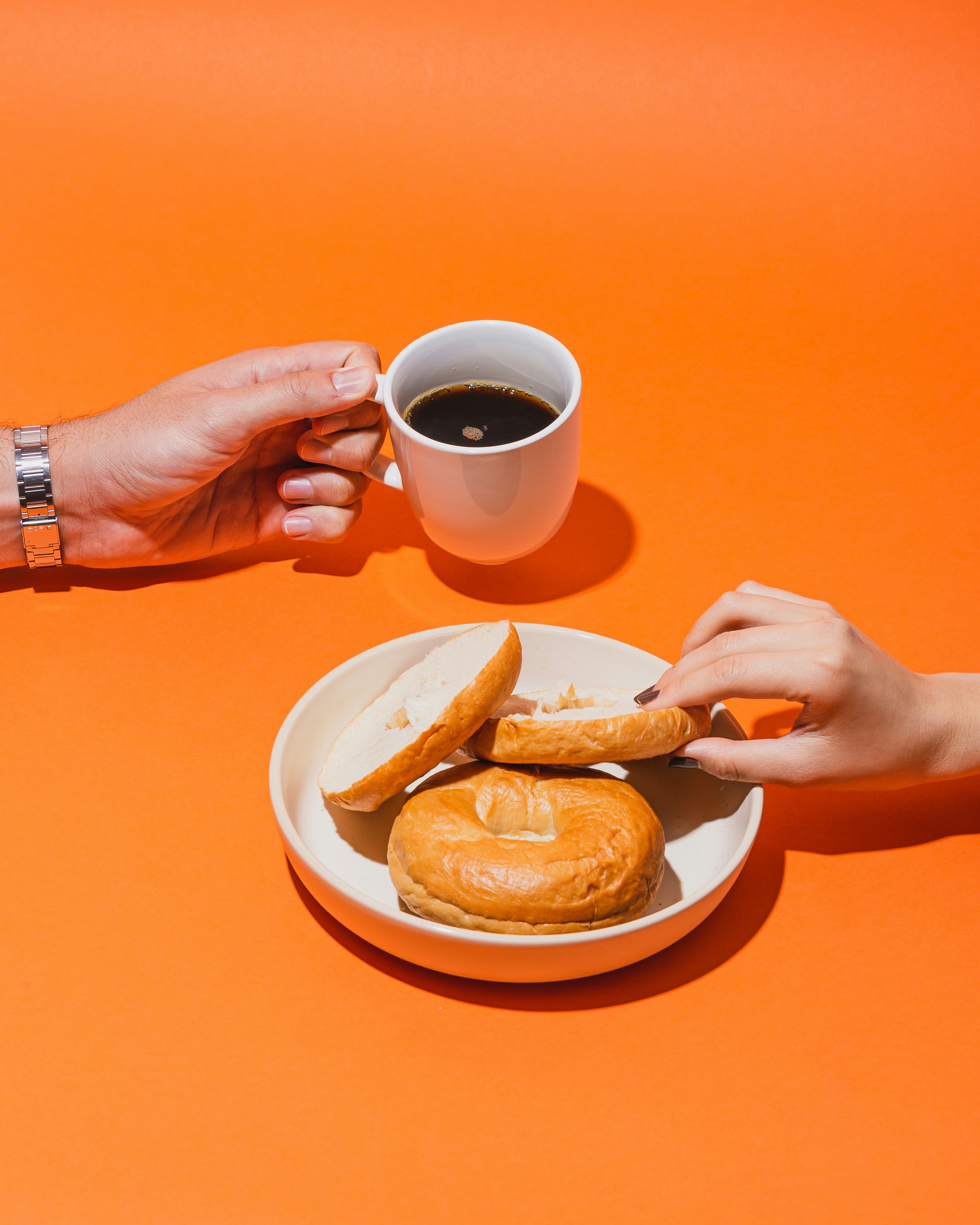 茶色の液体が入った白いセラミックのマグカップを持っている人