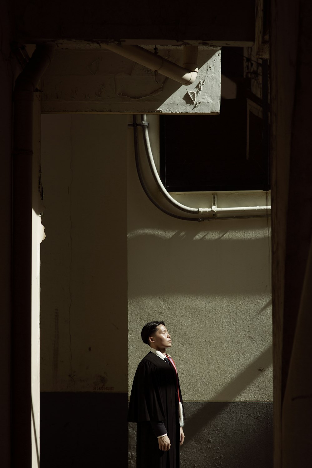 man in black and white jacket standing beside window