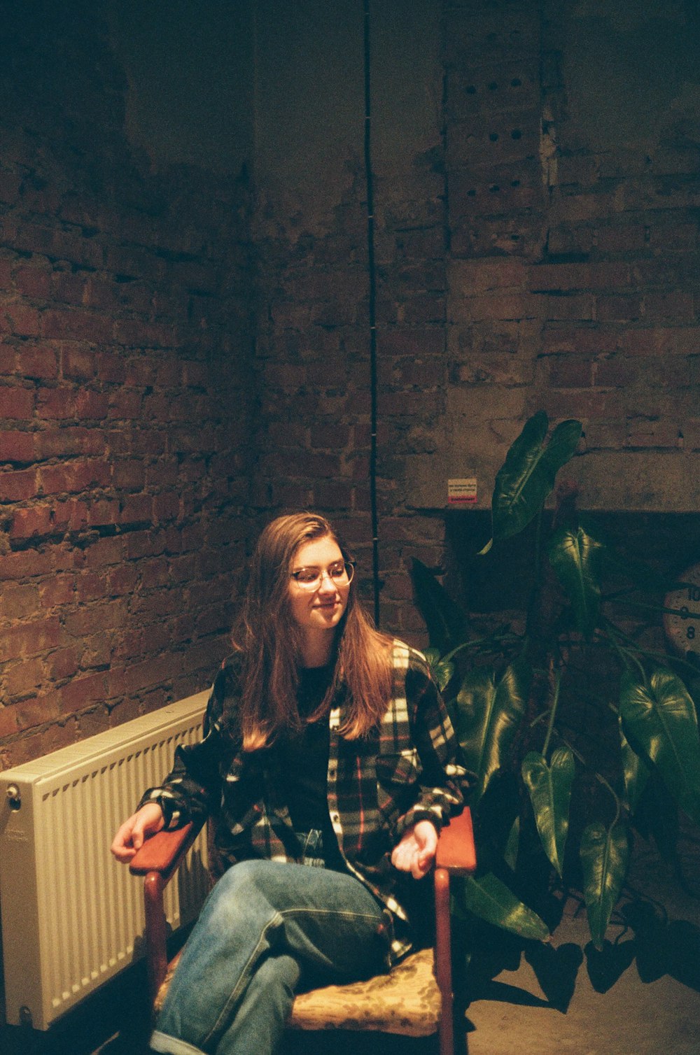 a woman sitting in a chair next to a plant