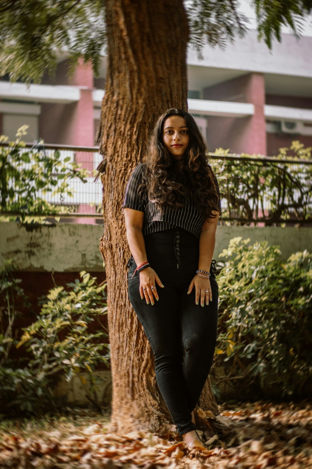 woman in black dress standing beside brown tree