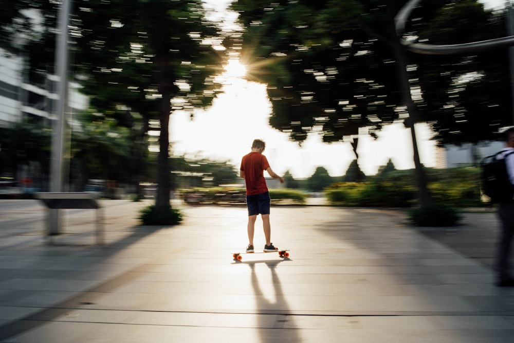 Mann in rotem T-Shirt und blauer Jeans spielt tagsüber Skateboard