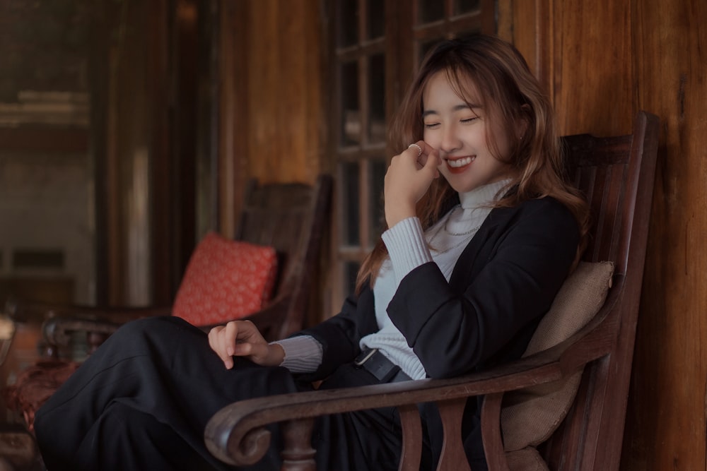 woman in black blazer sitting on brown wooden armchair