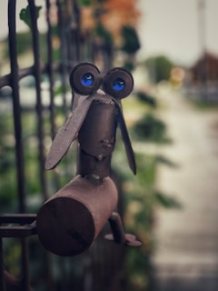 A whimsical garden decoration featuring a metal bird perched on a leafy stake