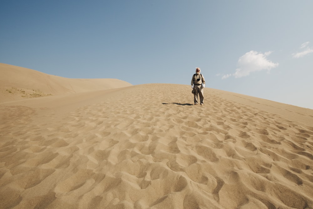 man in black jacket walking on desert during daytime