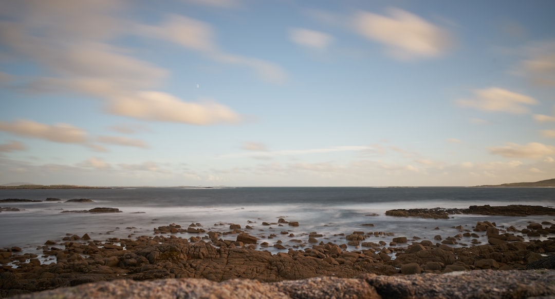 brown rocks on seashore under blue sky during daytime