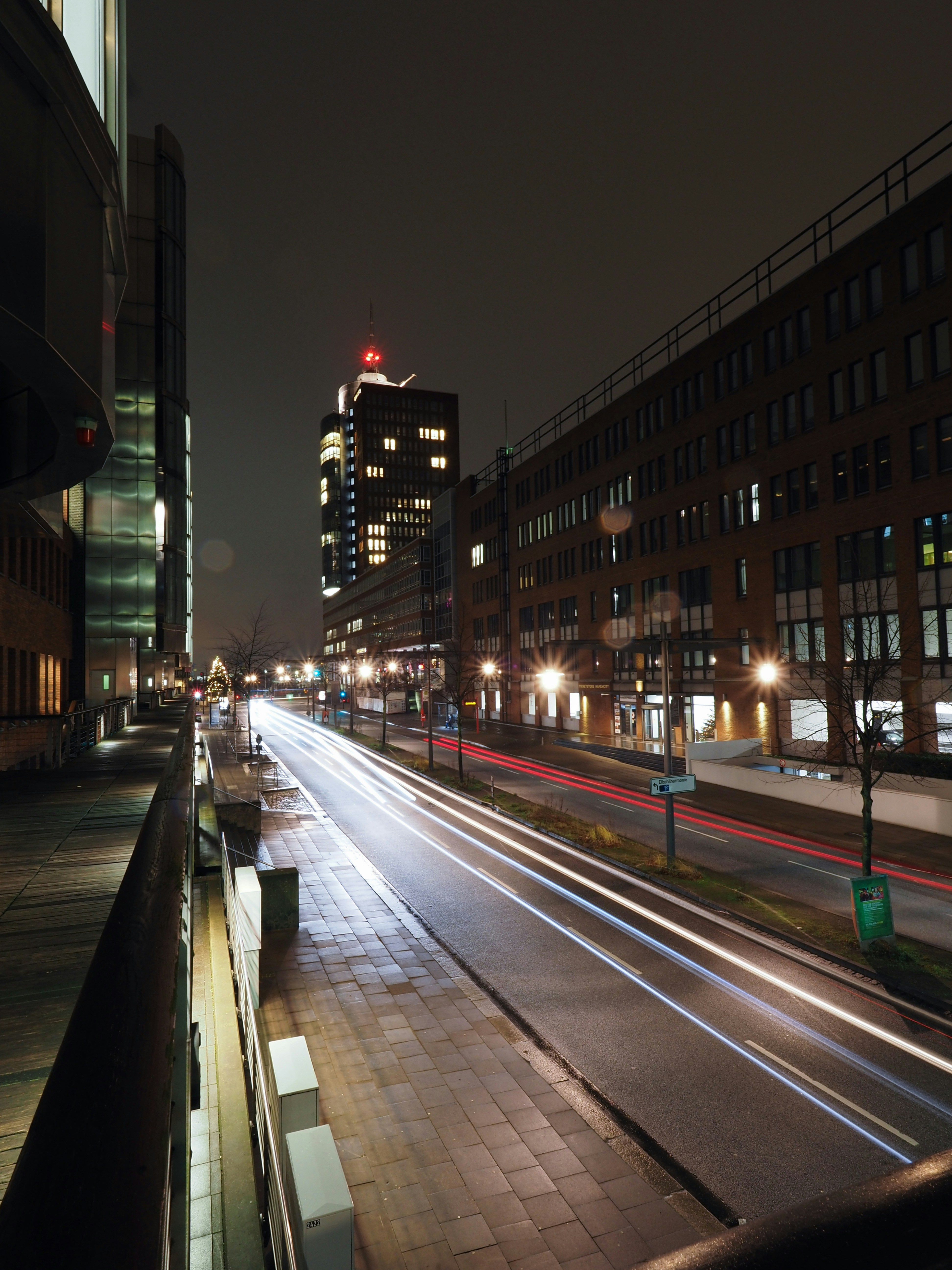 Long-exposure night photography of a city street with light trails and dark silhouettes