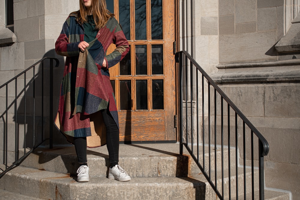 woman in red and black scarf standing on gray concrete stairs