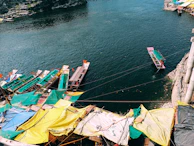 Colorful traditional boats docked along the riverbank in a lively village scene.