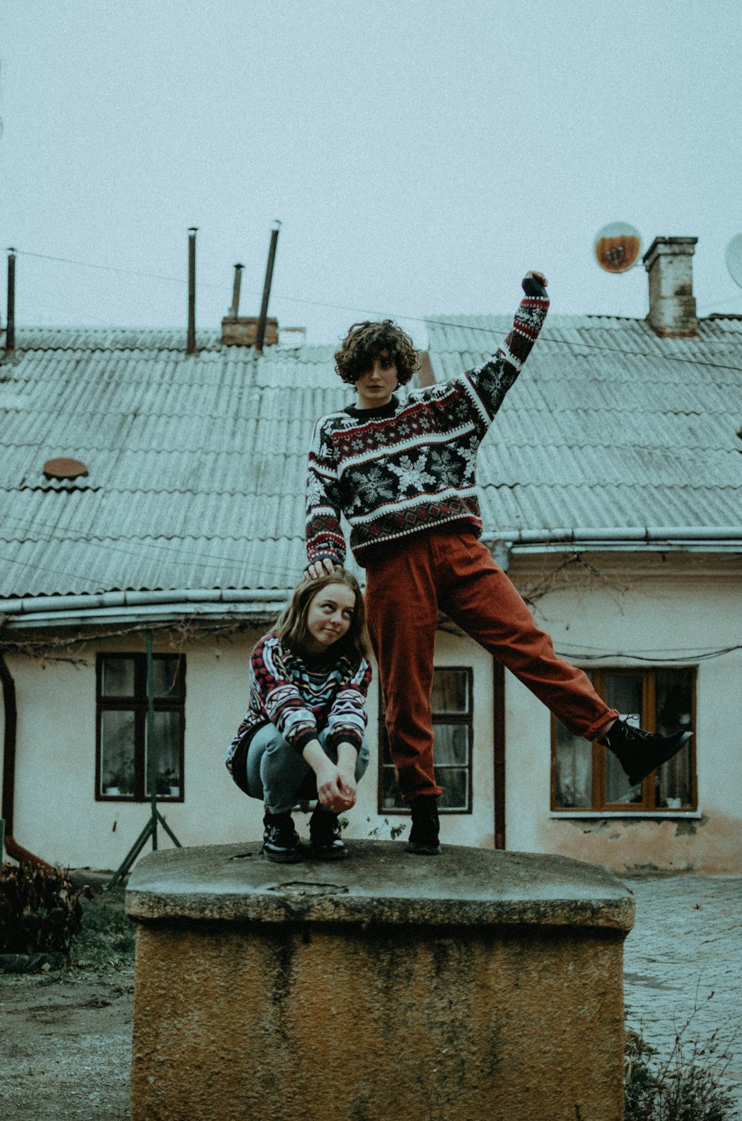 boy in black and white sweater and red pants jumping on gray concrete stairs during daytime