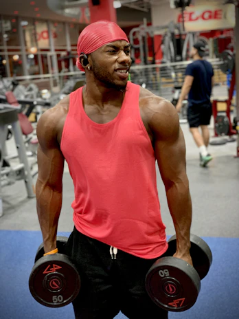 A smiling client in workout gear, lifting weights with determination in a modern gym.