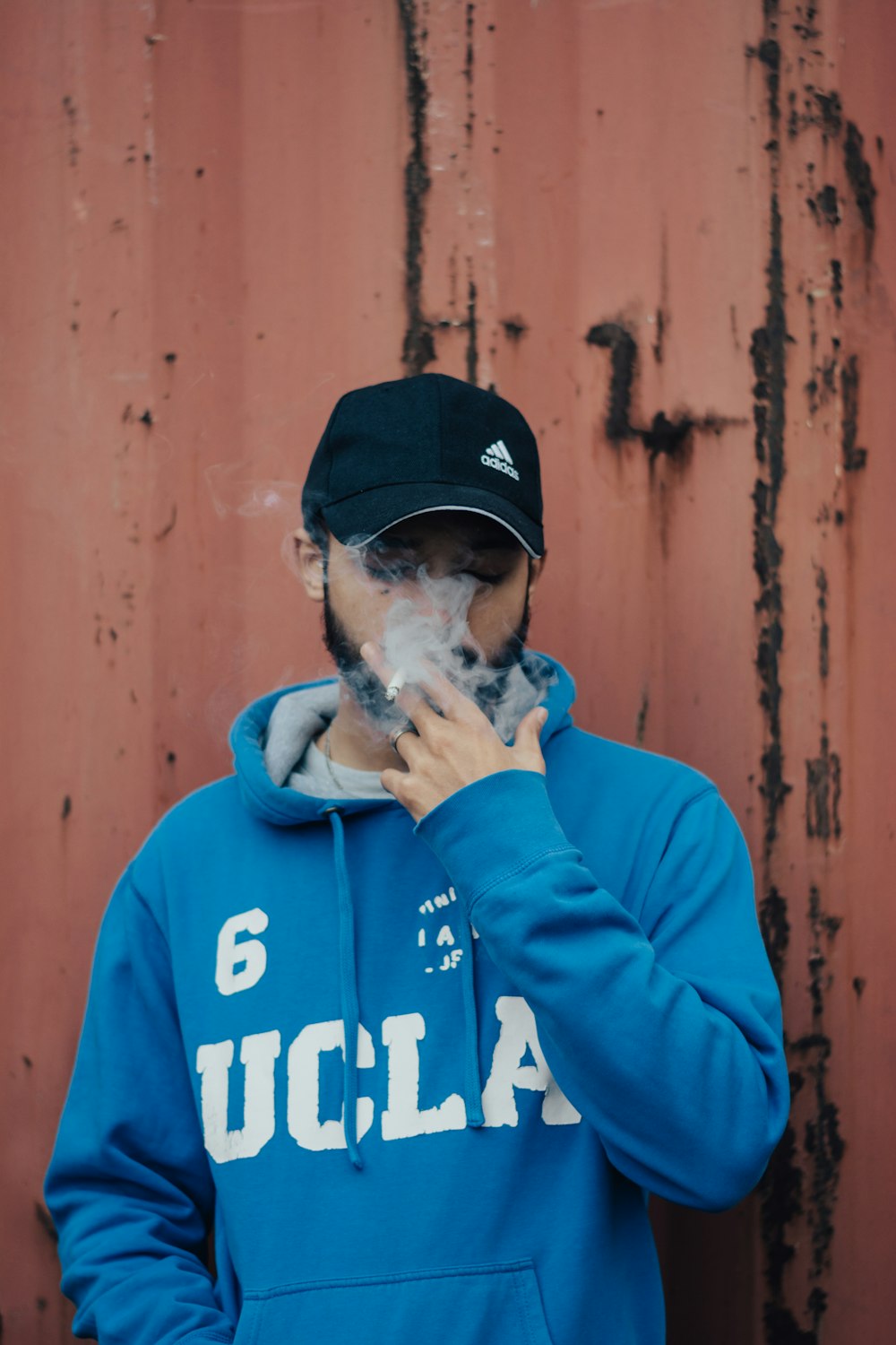 man in blue and white pullover hoodie wearing black cap
