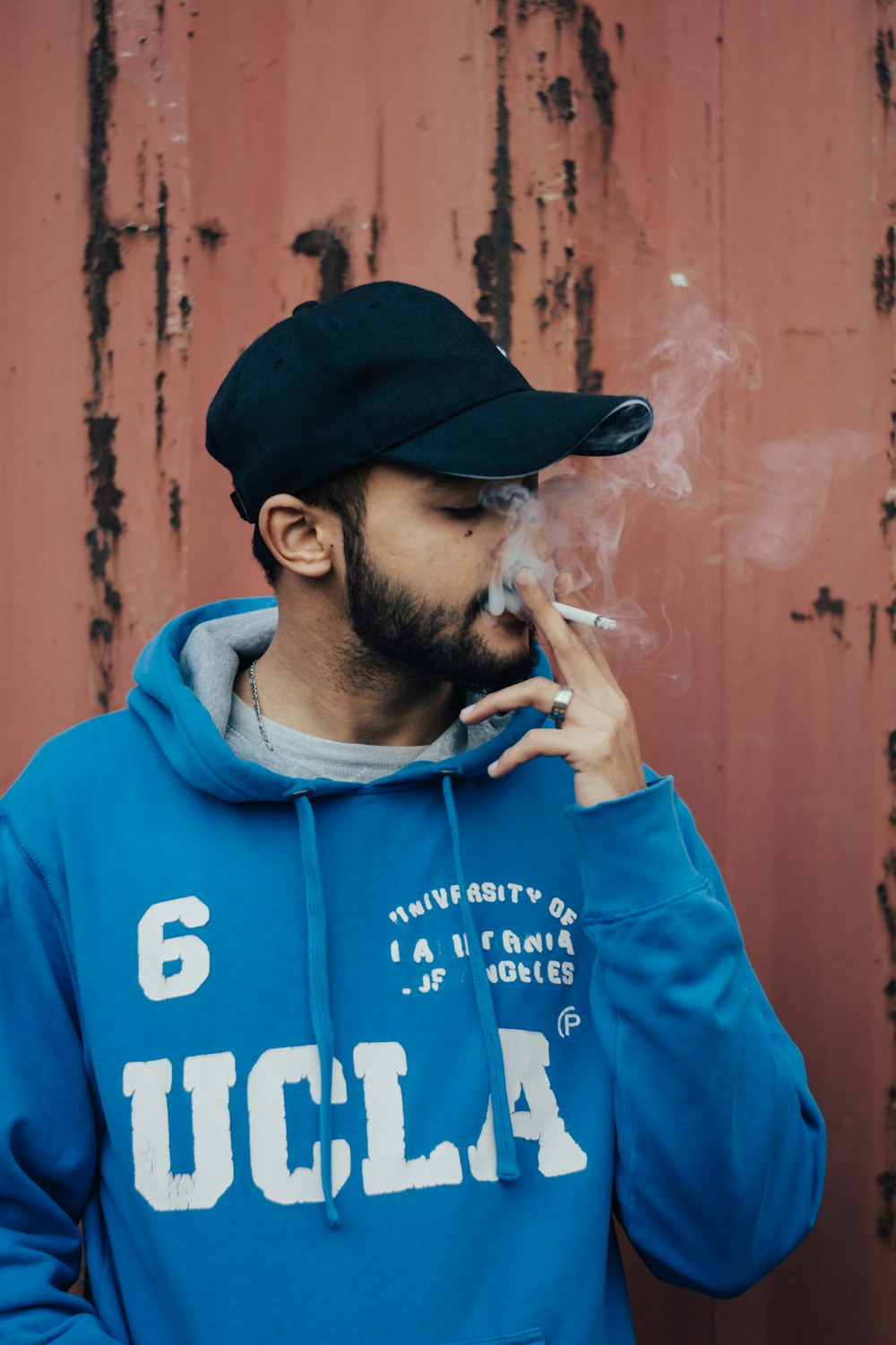 Mann in blauem Kapuzenpulli raucht Zigarette