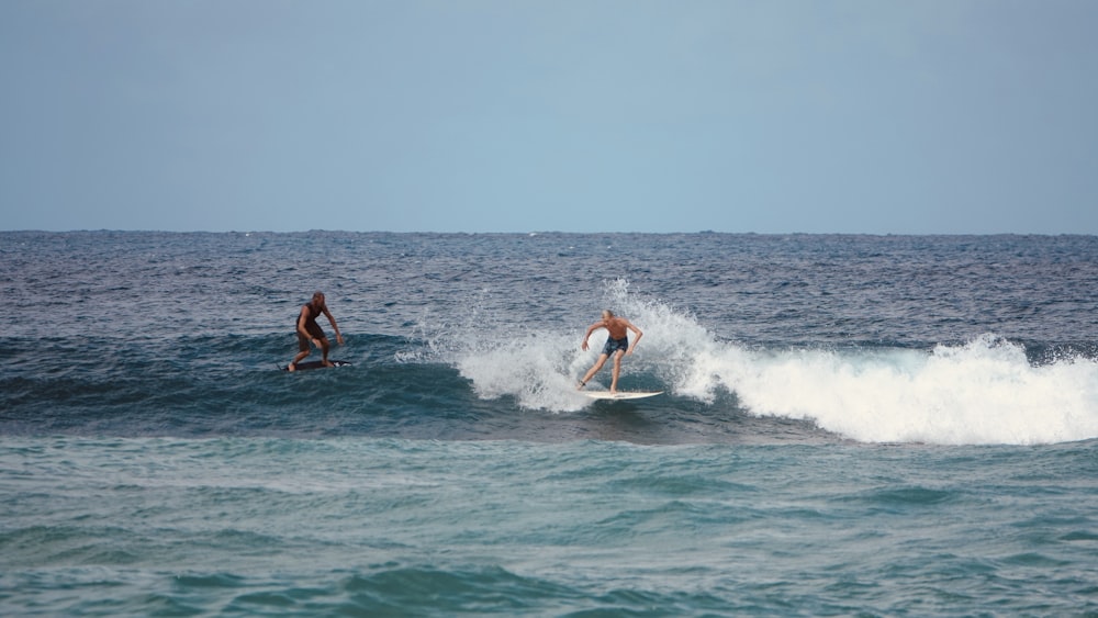 2 men surfing on sea during daytime