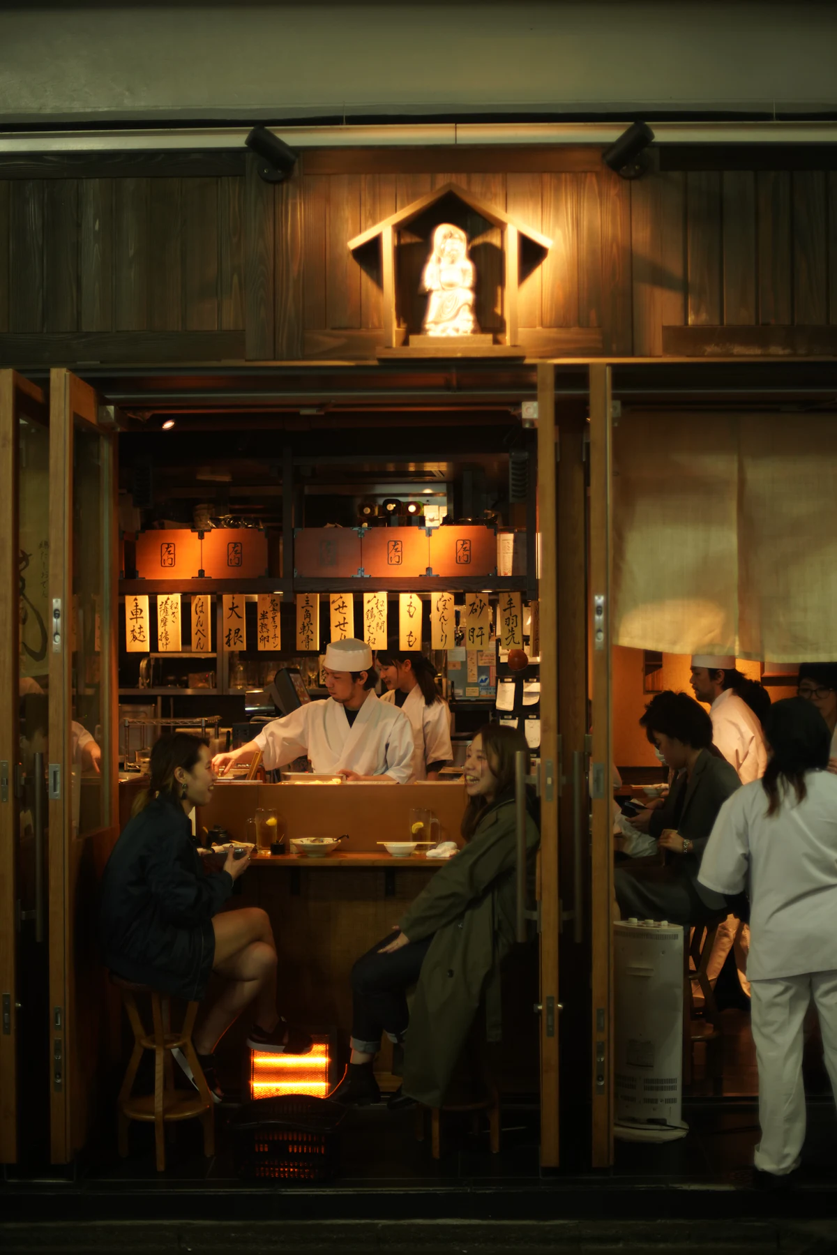 木のぬくもりが感じられる居酒屋のカウンター席と暖色の照明