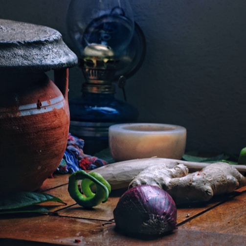 A moody kitchen scene with jars of fermenting vegetables, a single plate of rustic food, and vintage decor elements.