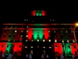 A large office building wrapped in colorful synchronized Christmas lights glowing against the night sky.