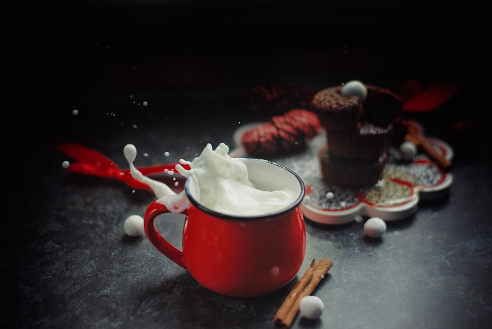 white and red ceramic mug with white powder on gray table