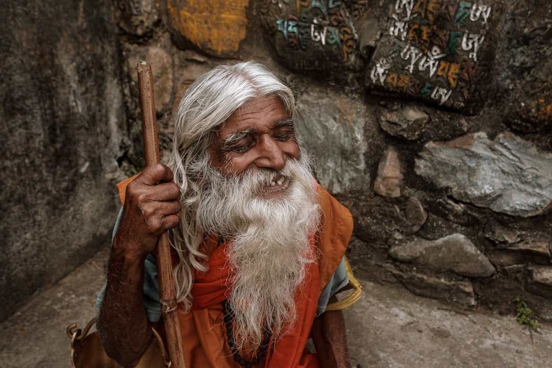 man in orange and yellow robe holding brown stick