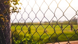 A friendly technician measuring a property for chain-link fence installation on a sunny day.