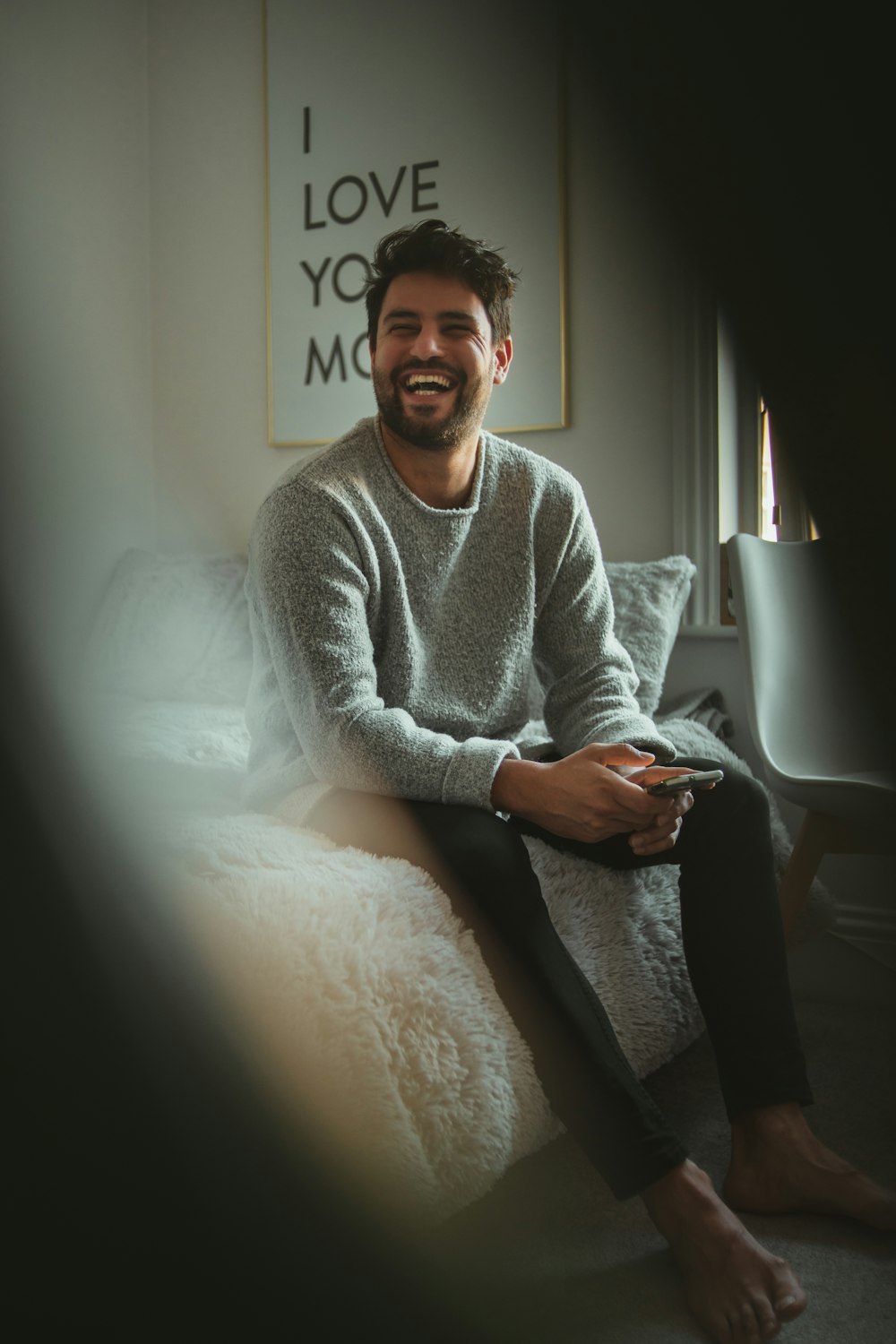 man in gray sweater sitting on bed