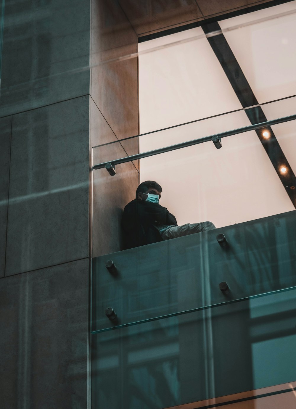 man in black jacket standing beside glass wall