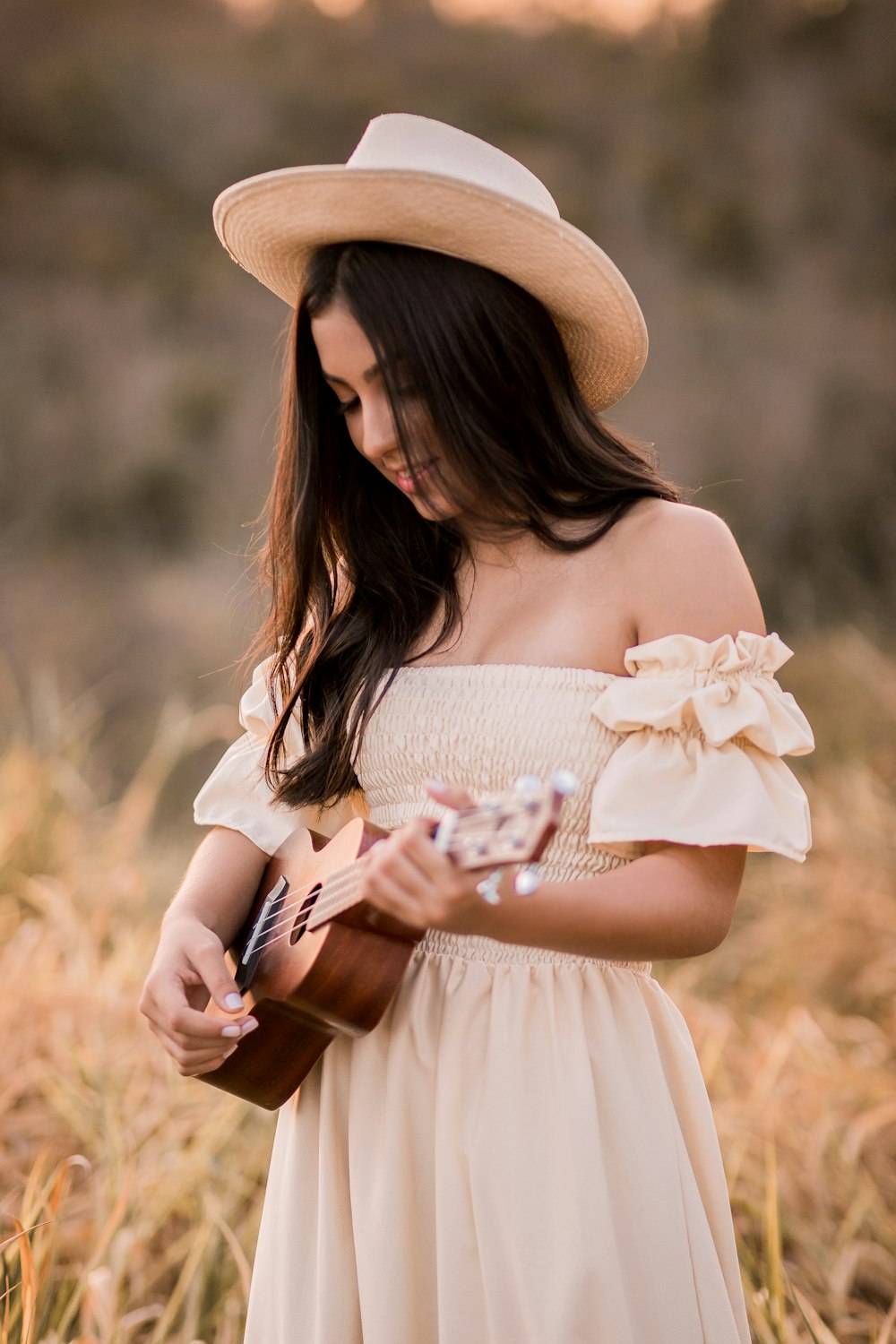 woman in white dress wearing brown sun hat holding white flower bouquet