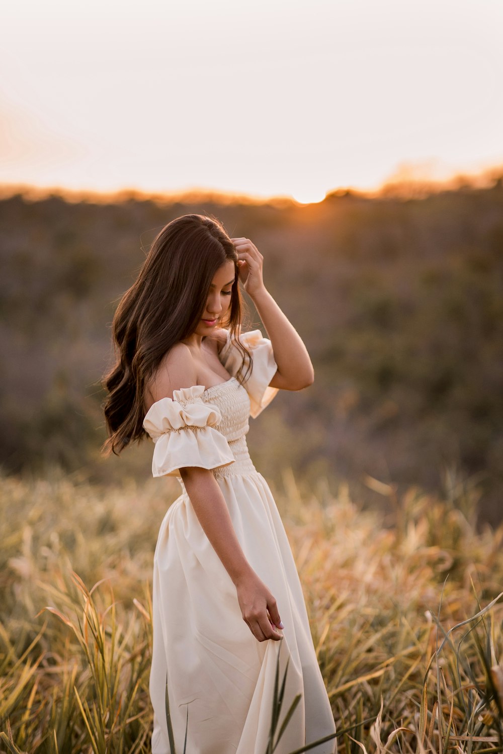 woman in white dress standing on brown grass field during daytime