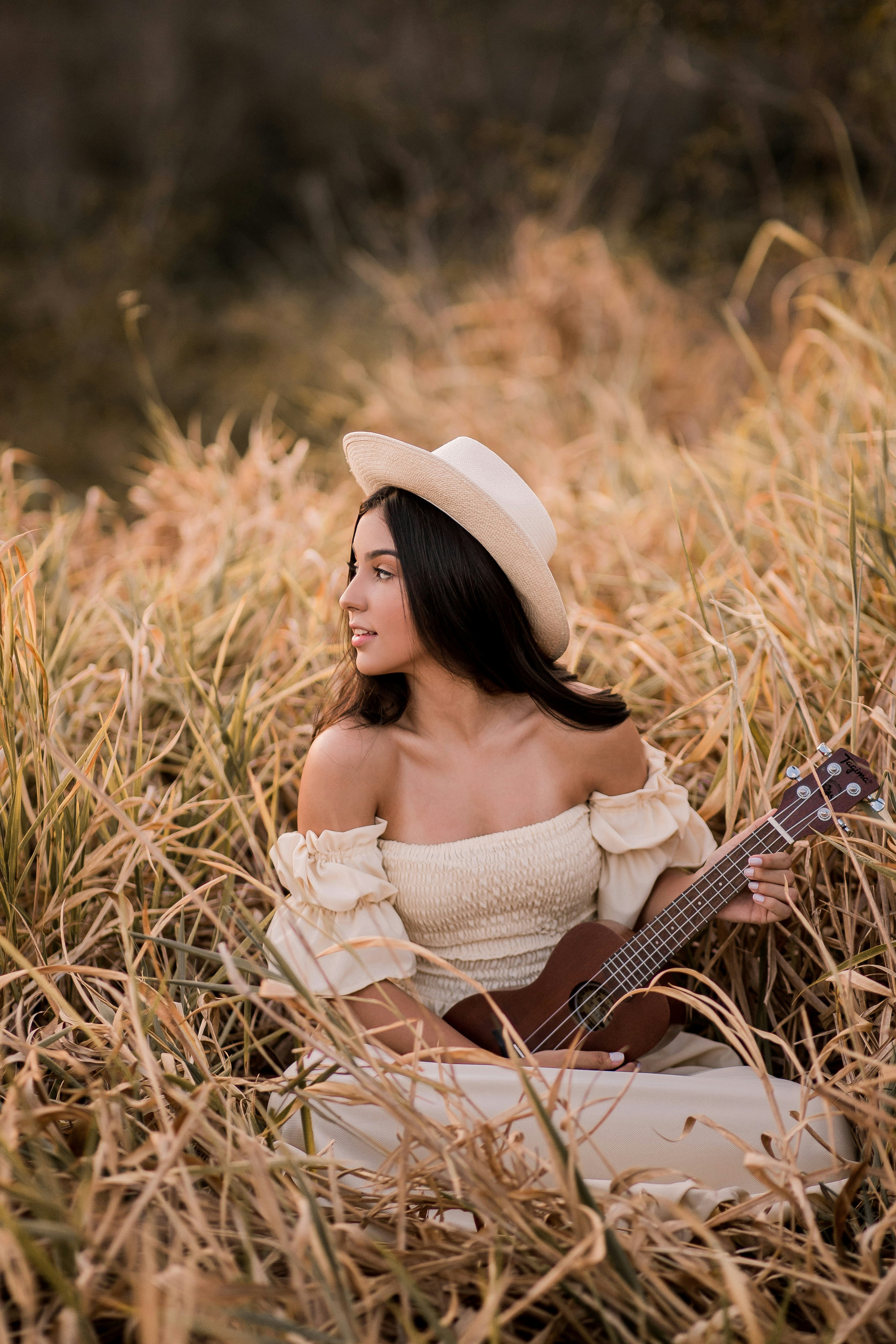 woman in white off shoulder dress holding brown acoustic guitar