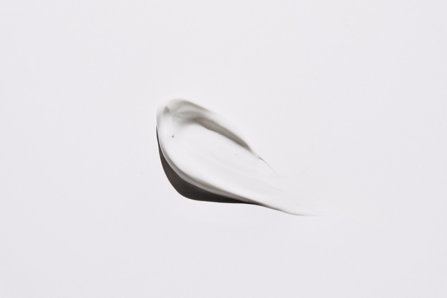 A drop of moisturizer spread out on a white background.