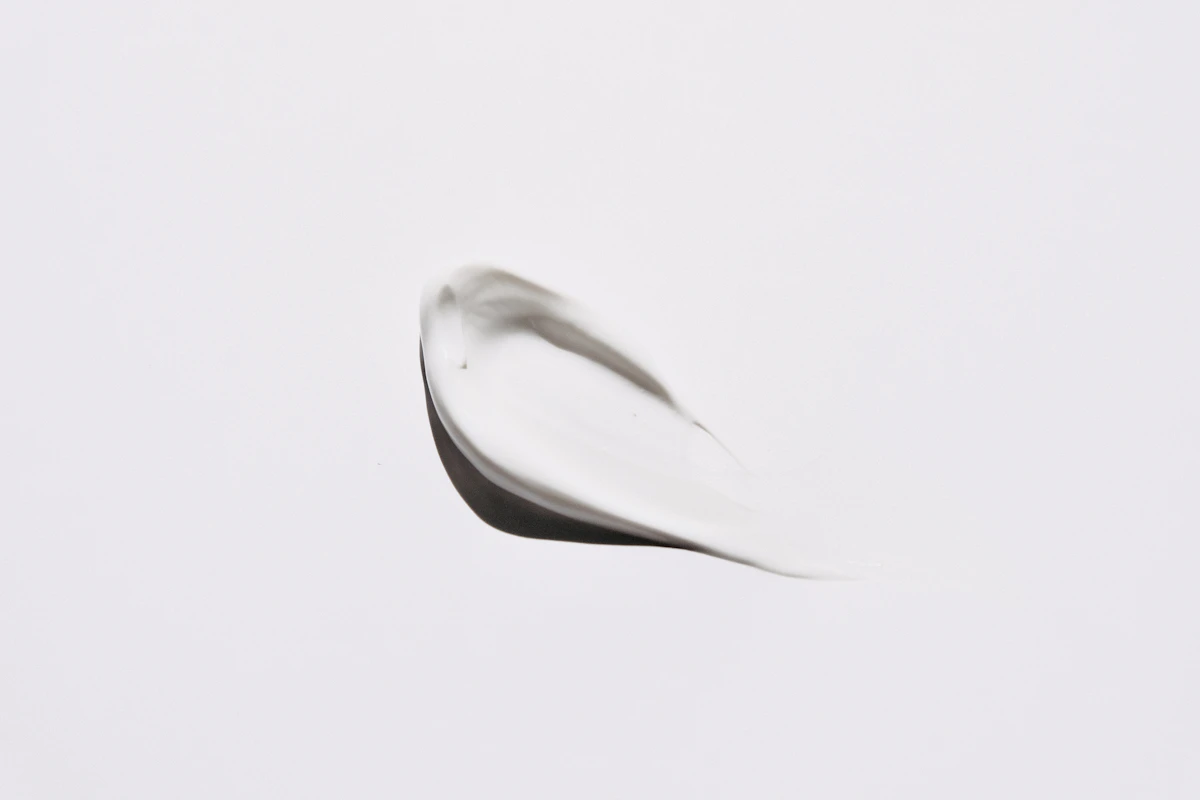 Spalmo bianco di crema cosmetica su sfondo bianco