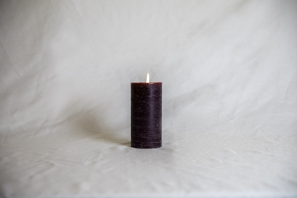 red pillar candle on white textile