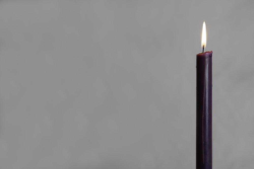 lighted candle on white wall