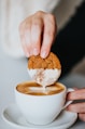 person holding white ceramic mug with brown and white liquid