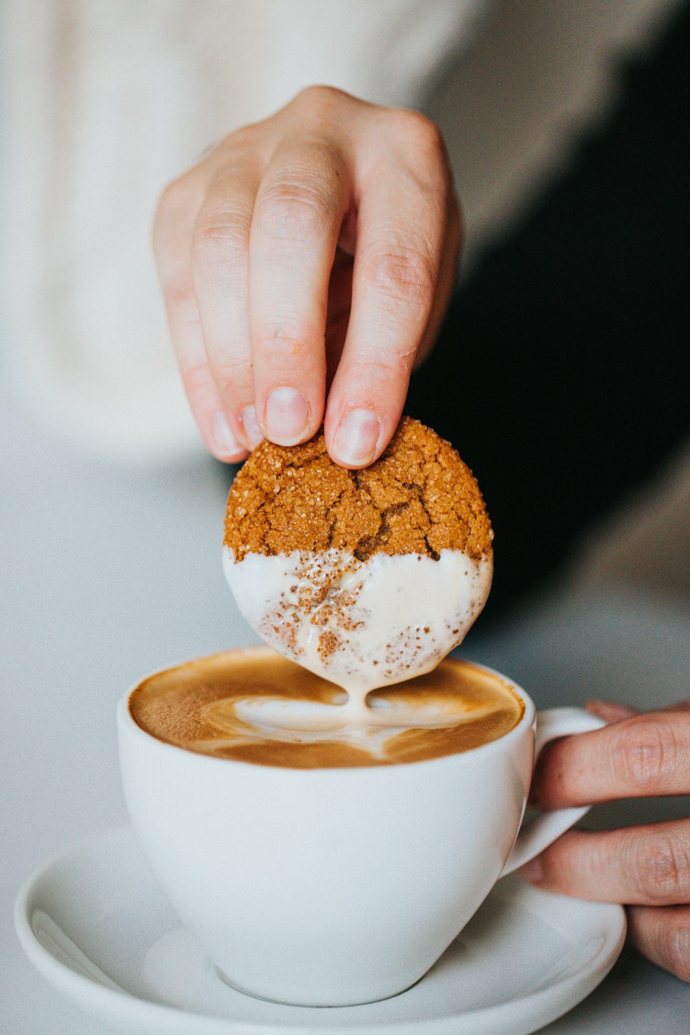 person holding white ceramic mug with brown and white liquid