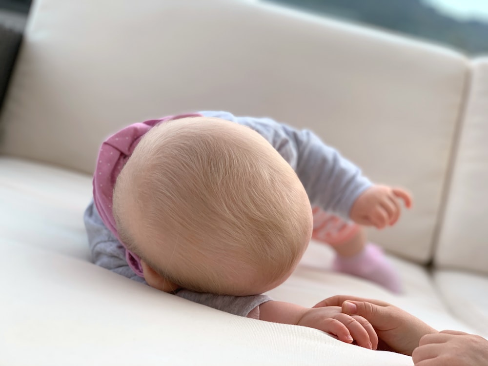 baby in blue long sleeve shirt lying on bed