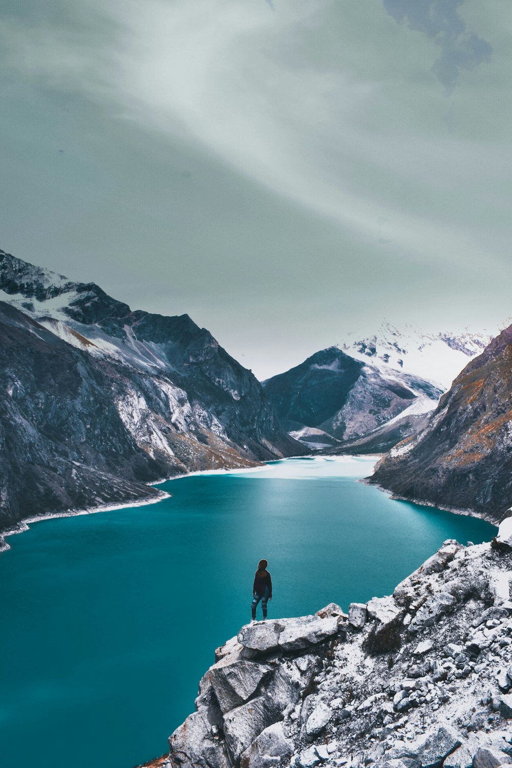 person sitting on rock near lake during daytime