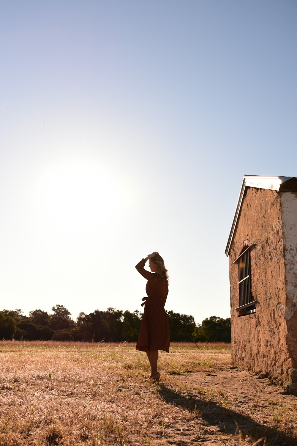 woman in brown dress standing on brown grass field during daytime