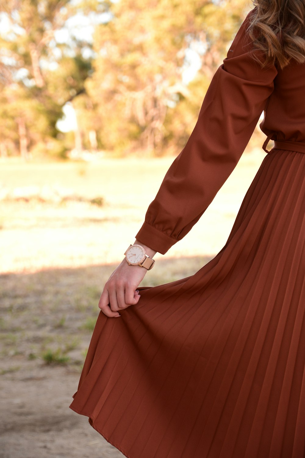 Frau im braunen langärmeligen Kleid mit silberner runder Analoguhr