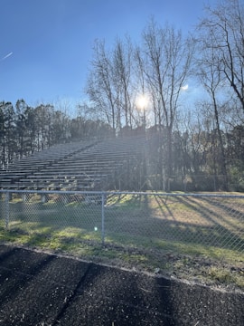 Sturdy wooden bleachers set up in an outdoor park during a sunny day.