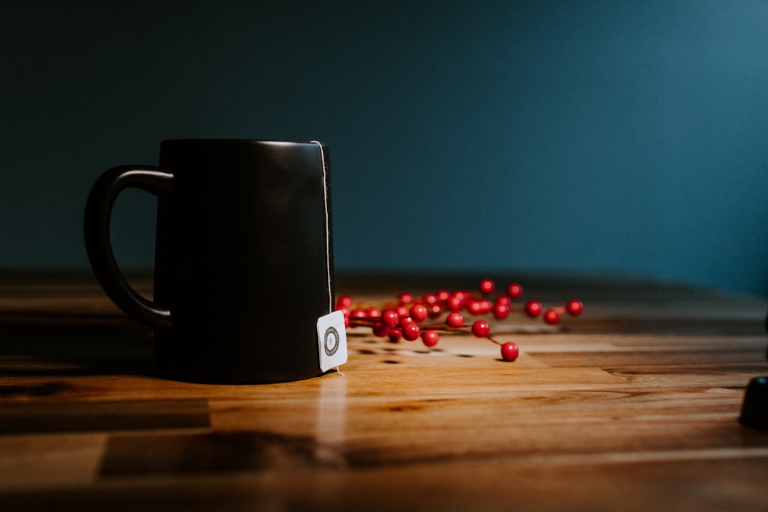 black ceramic mug on brown wooden table, Tea mug on a wooden table with berries