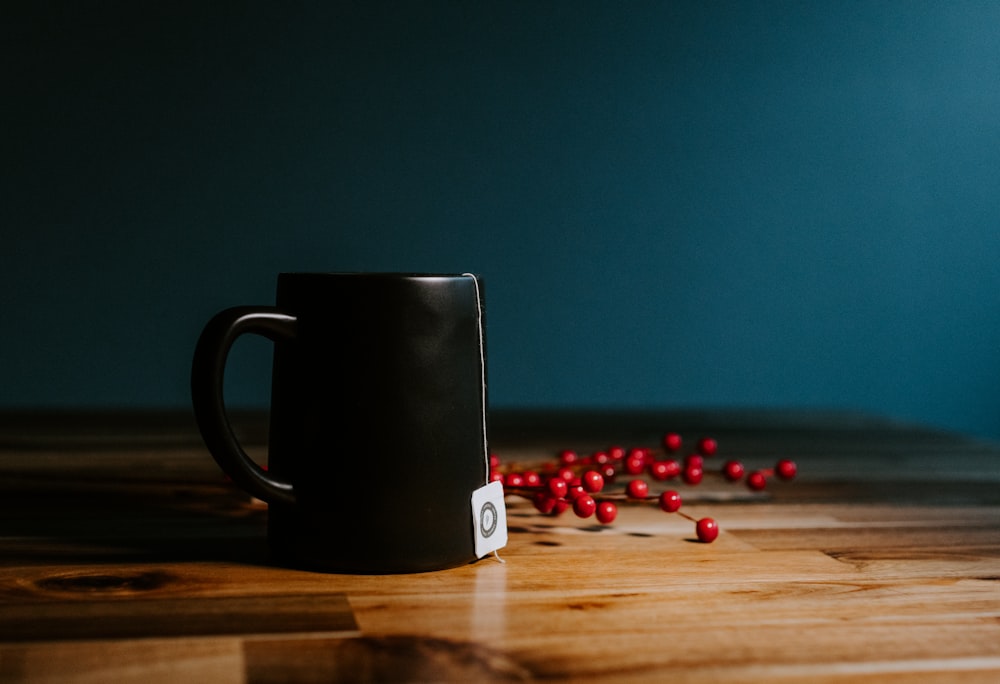 Taza de cerámica en blanco y negro con píldora de medicación roja y amarilla sobre mesa de madera marrón